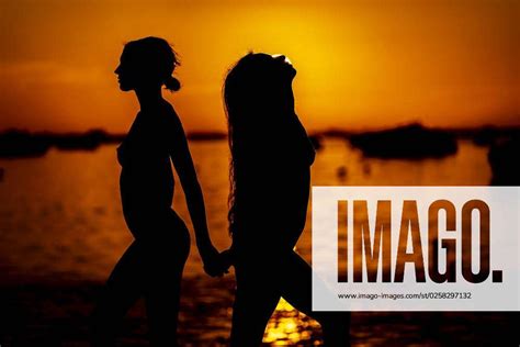 two lovely nude latin models are silhouetted against the rising sun on a romantic caribbean beach