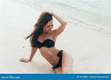 Tanned Girl In Black Swimsuit Posing On Sandy Beach Near Ocean Beautiful Model Sunbathes And