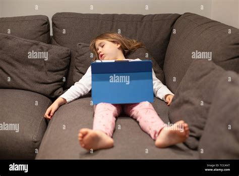 Fünf Jahre alte blonde Kind im Schlafanzug schlafen liegen auf der Coach mit digitalen Tablette