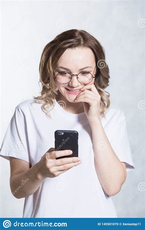 Perplexed And Worried A Beautiful Young Woman Is Holding A Smartphone