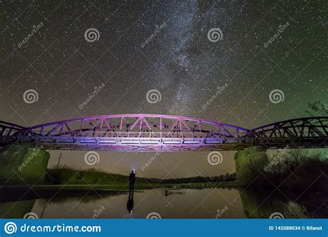 Back View Of Man With Flashlight Standing On River Bank Under