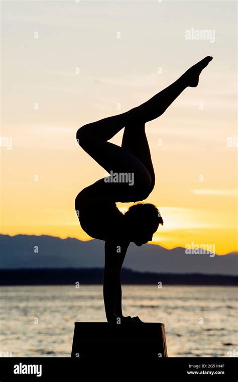 Silhouette Of Woman Doing Acrobatic Handstand Pose Against Sea At