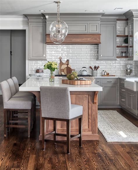 A Kitchen With Gray Cabinets And Wooden Floors An Island Table
