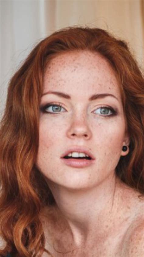 a woman with freckled hair and blue eyes looks at the camera while posing for a photo