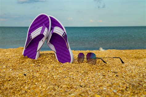 Pair Of Flip Flops And Sunglasses On A Sandy Sea Beach Stock Photo
