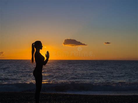 Woman Doing Yoga Meditation And Relaxing Breathing Exercises At Beach