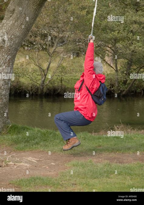 Old Swinger In Red Grey Haired Lady On Rope Swing In Tree Beside River