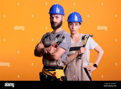 serious construction workers posing with pair of pliers and hammer holding slegdehammer and
