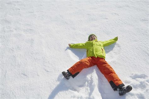 Young Boy Making Snow Angel In Snow Stock Photo