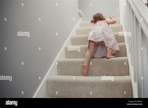 Rear View Of A Little Girl Climbing Up The Stairs In The House She Is