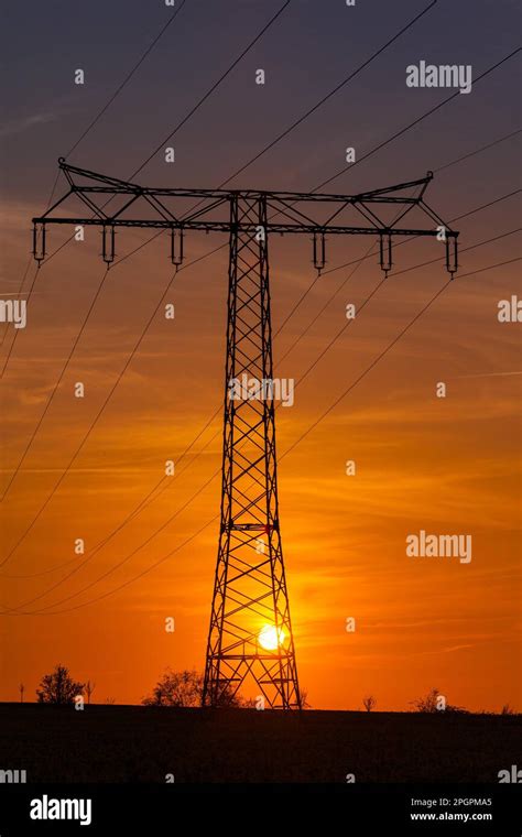 High Voltage Power Line High Voltage Pylon In The Sunset Stock Photo