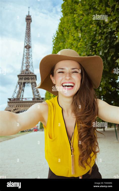 Smiling Young Tourist Woman In Yellow Blouse And Hat Taking Selfie