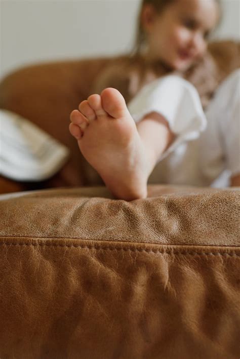 Crop Adorable Barefoot Child Resting On Cozy Sofa At Home · Free Stock