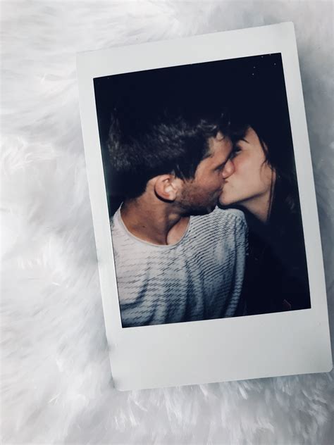 A Man And Woman Kissing In Front Of A Polaroid Frame On A Fluffy White