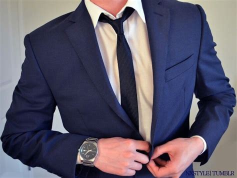 rolling little messy with black tie on a navy blue suit with no pocket square while buttons