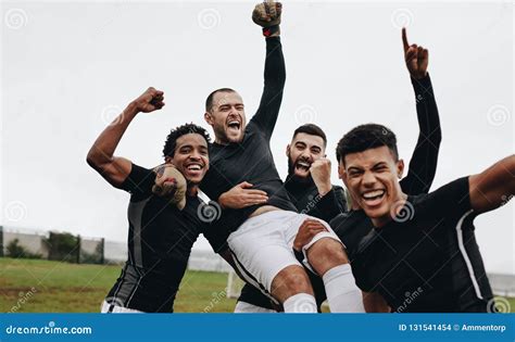 Group Of Happy Soccer Players Celebrating A Win By Lifting Their Goalkeeper Footballers