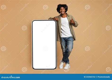 Hnadsome Smiling Black Guy Leaning On Big Smartphone With Blank White