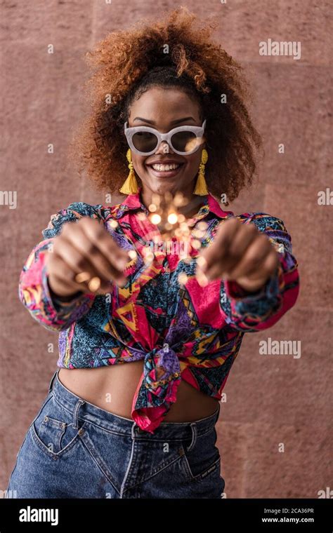 Happy Young Black Woman In Bright Trendy Clothes Smiling For Camera And Showing Blurred