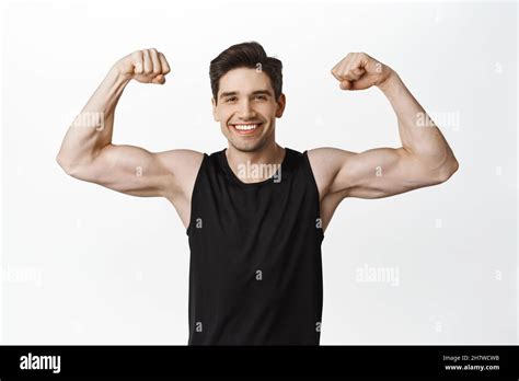 Sport And Gym Smiling Young Healthy Man Flexing Biceps Showing Strong