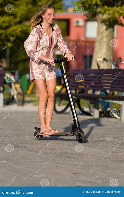 Beautiful Long Hair Teenager Girl Enjoys Summer Vacation Riding Her Electric Scooter Stock