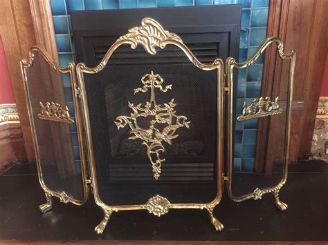 An Ornate Gold Fireplace Screen In Front Of A Fire Place