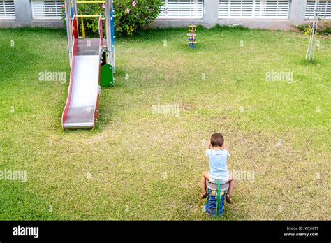 Boy Playing Alone In A Playground On His Back Without His Parents Or