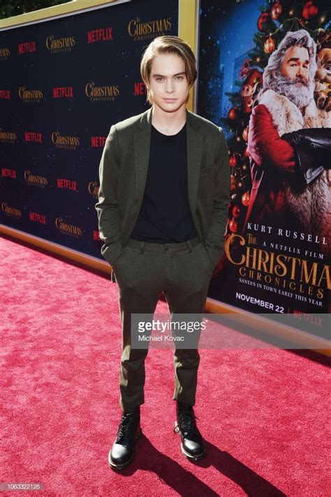 A Man In A Suit And Black Shirt Standing On A Red Carpet At The