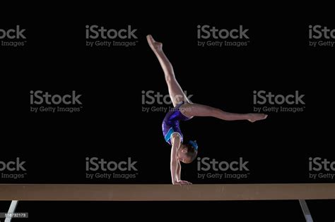 Young Female Gymnast Performing Handstand On Balance Beam