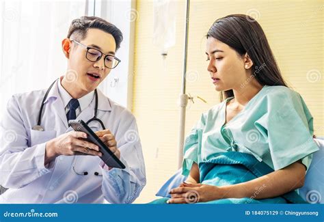asian male doctor talking to asian female patient in bed while explaining exam results in