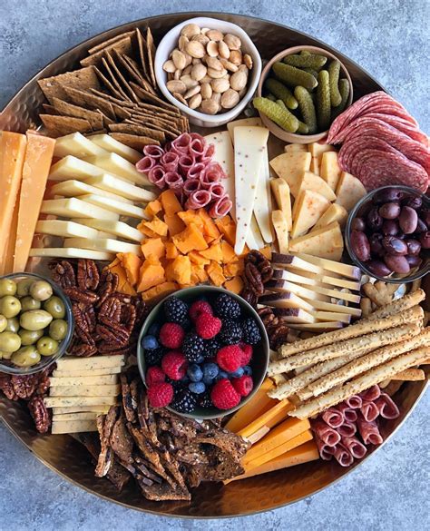 An Assortment Of Cheeses Crackers Nuts And Berries On A Platter