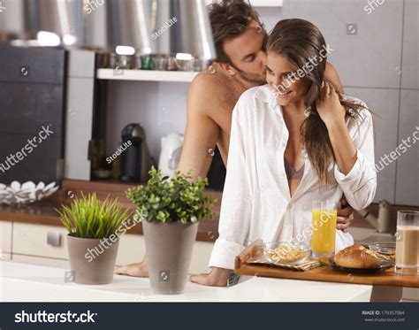 Loving Couple Kissing In The Kitchen In The Morning Stock Photo