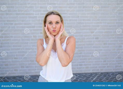 Simpering Blond Woman Pursing Her Lips For The Camera Stock Photo