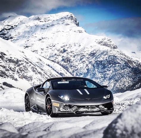 A Grey Sports Car Driving Down A Snowy Mountain Road In Front Of Snow