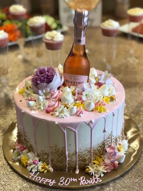 A Birthday Cake Decorated With Flowers And Icing Next To A Bottle Of Booze