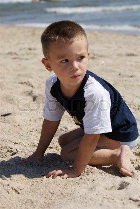 Young Boy 3 Years Old Sits On Seacoast And Playing Stock Photo