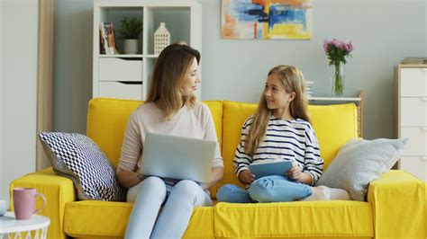 Vídeo Gratis Madre E Hija Rubias Sentadas En Un Sofá Amarillo Mientras Usan Una Computadora