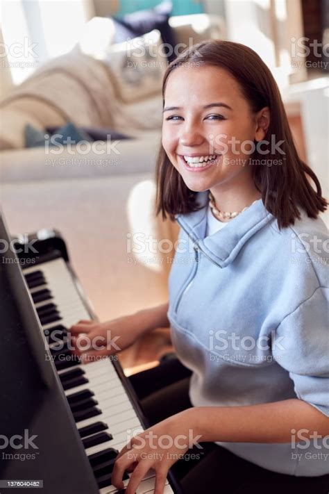 Portrait Of Smiling Teenage Girl At Home Playing The Piano Stock Photo