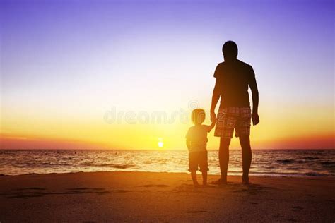 Padre E Hijo En La Playa De La Puesta Del Sol Imagen De Archivo