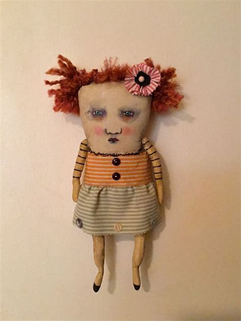 A Doll With Red Hair And Blue Eyes Hanging On The Wall Next To A White Wall