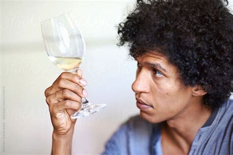 Holding wine glass stock images from offset. Mixed race man holding a glass of white wine looking at the quality of the wine in the glass ...