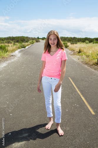 A Teenage Girl Travels Barefoot On An Empty Road Stock Photo And