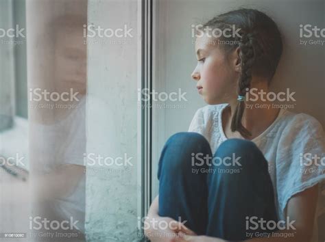 Sad Little Girl Sitting Near The Window Stock Photo Download Image