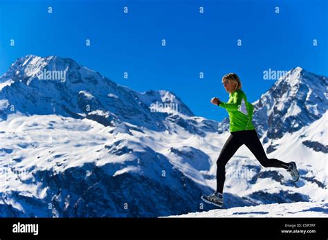 A Women Jogging Across Snowy Alpine Mountains Stock Photo Alamy