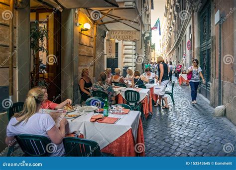 People And Families Sitting In Outdoor Dinning Area In Italian