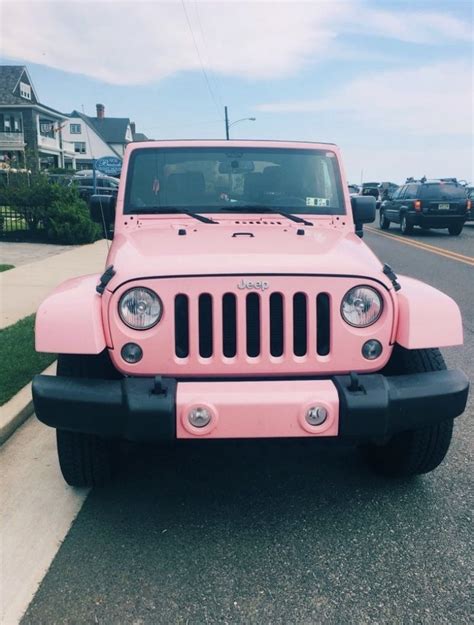 A Pink Jeep Is Parked On The Side Of The Road In Front Of Some Houses