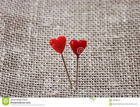 Pair Of Sharp Pins In The Form Of Red Hearts Stuck In The Rough Stock