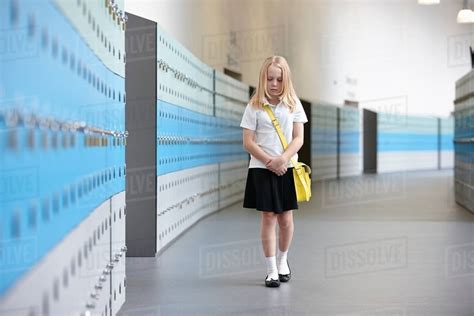 Unhappy Schoolgirl Walking Alone In School Corridor Stock Photo