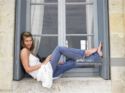 Young Woman Sitting With Feet Up On Window Sill Smiling Side View