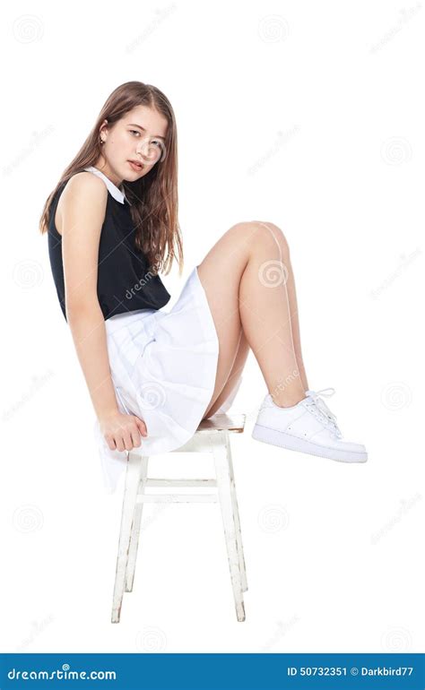 Menina Nova Da Forma Na Saia Branca Que Senta Se Na Cadeira Isolada