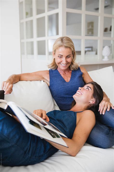 Happy Mother And Daughter Looking At A Photo Album Together On The